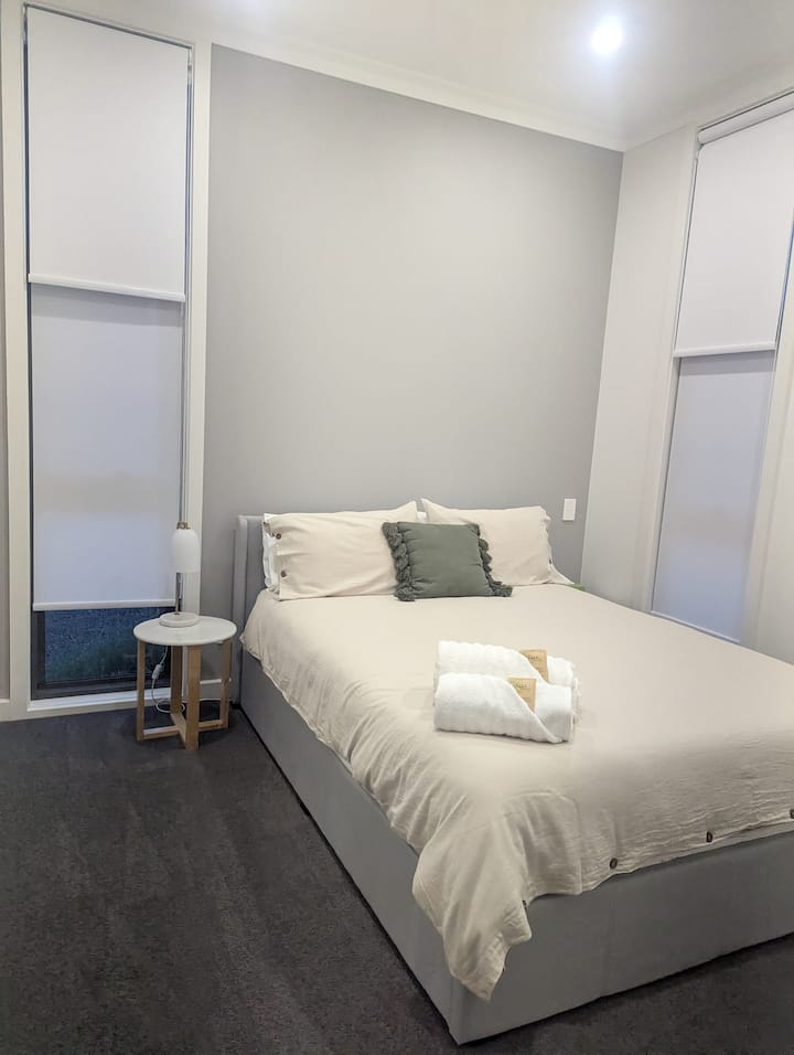 Unwind in Bedroom 2, featuring a cozy queen bed with fresh towels. Enjoy total comfort with reverse cycle air conditioning for perfect climate control and a handy wardrobe for all your storage.