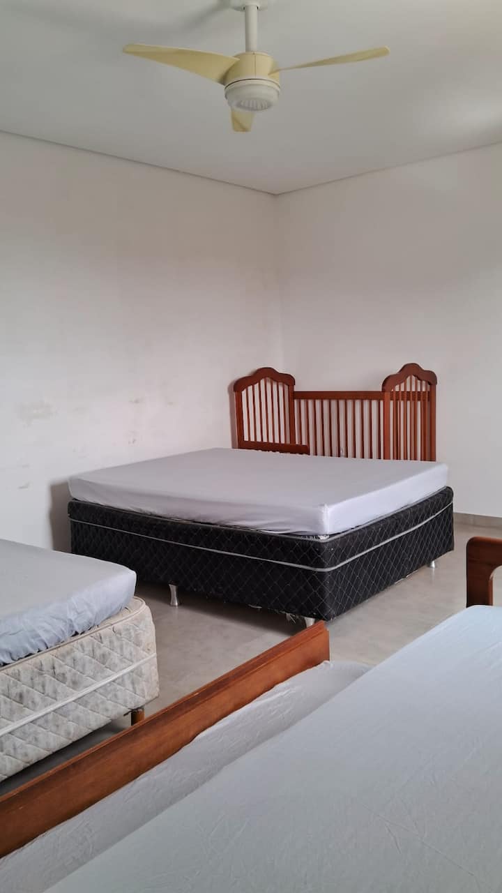 Prvá spálňa na druhom poschodí s dvoma manželskými posteľami, vysúvacou posteľou, detskou postieľkou a stojanom na batožinu so stropným ventilátorom.