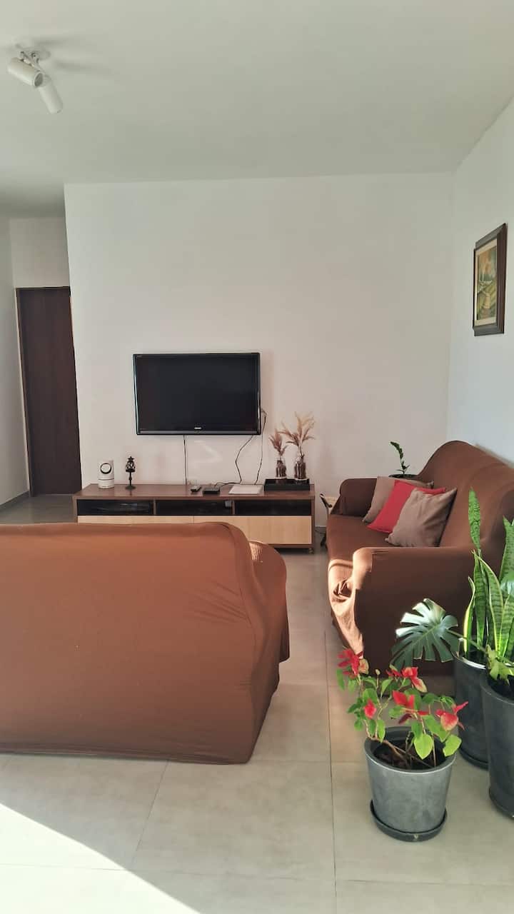 Obývacia izba na prízemí s pohovkou a televízorom.