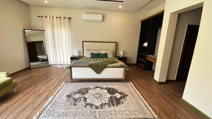 Opustite se u našoj glavnoj spavaćoj sobi okupanoj prirodnim svjetlom.  Prozori od poda do stropa i privatni balkon pružaju prekrasan pogled na Margalla Hills. Uživajte u svom omiljenom filmu na TV-u, razmazite se ili jednostavno uživajte u ljepoti s kauča.