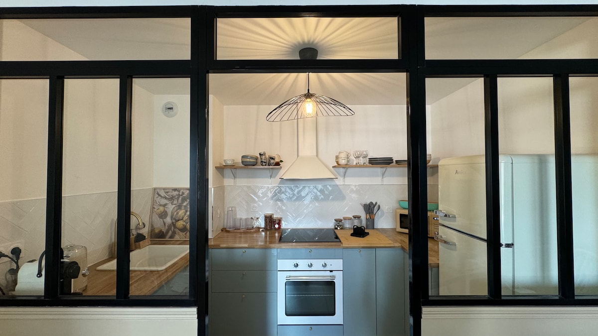 The kitchen features a modern design with sleek cabinetry and a wooden countertop. A vintage-inspired refrigerator adds character. Open shelving displays various dishware, while a pendant light provides ambient illumination. A stove and oven are visible, along with essential cooking utensils.