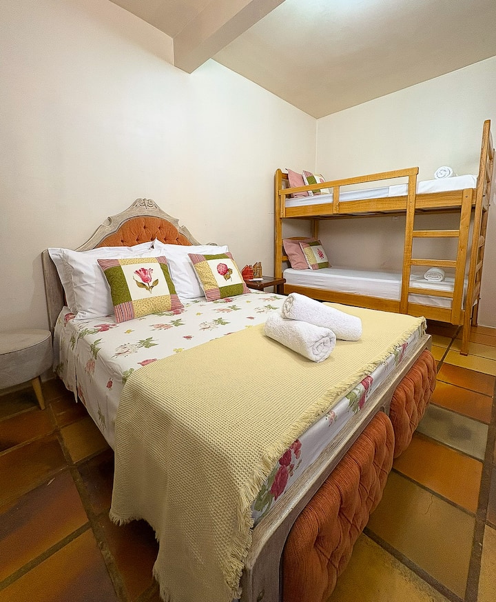 Este quarto com cama casal padrão e uma beliche, ar-condicionado e televisão smart, fica na segunda parte da casa próximo ao espaço gourmet 