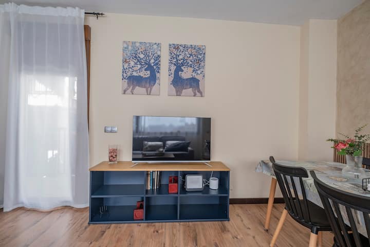 Salón con Smart TV, mueble azul y zona de comedor: práctico y con estilo.