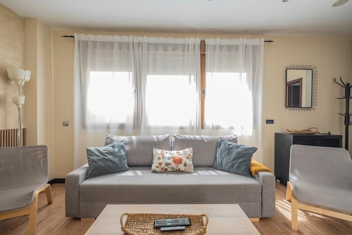Salón con sofá amplio y grandes ventanales: mucha luz para las tardes en casa.