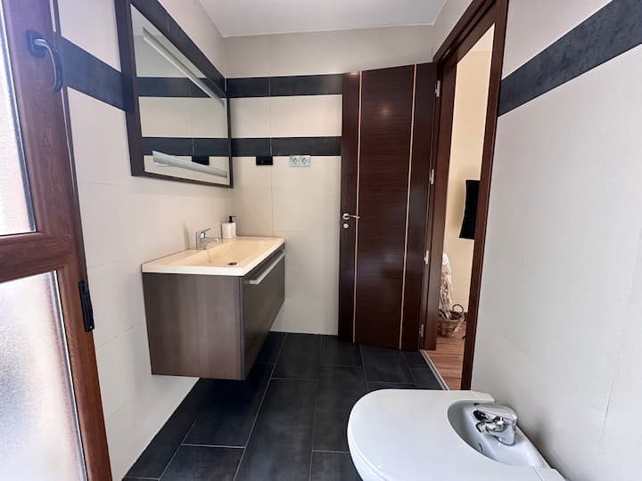 Baño con mueble de madera, espejo y bidé: cuidado y con mucho estilo.
