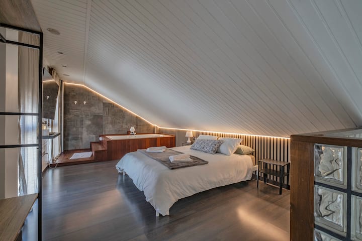 Dormitorio 1 con cama de matrimonio y jacuzzi al fondo: un espacio original y acogedor.