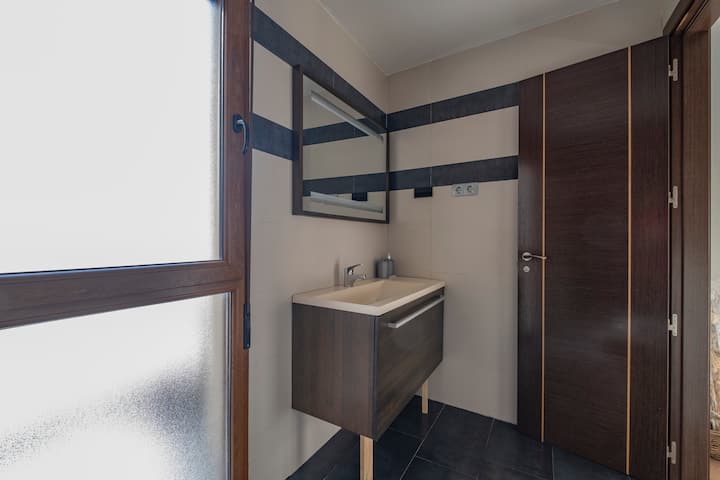 Baño completo con mueble de madera, espejo y lavabo: moderno y muy cuidado.