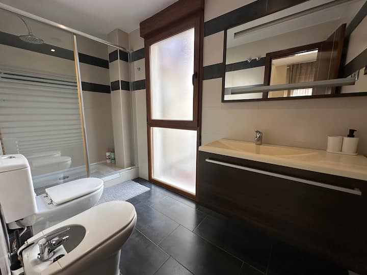 Baño con ducha, doble lavabo y espejo: espacioso y con acabados modernos.