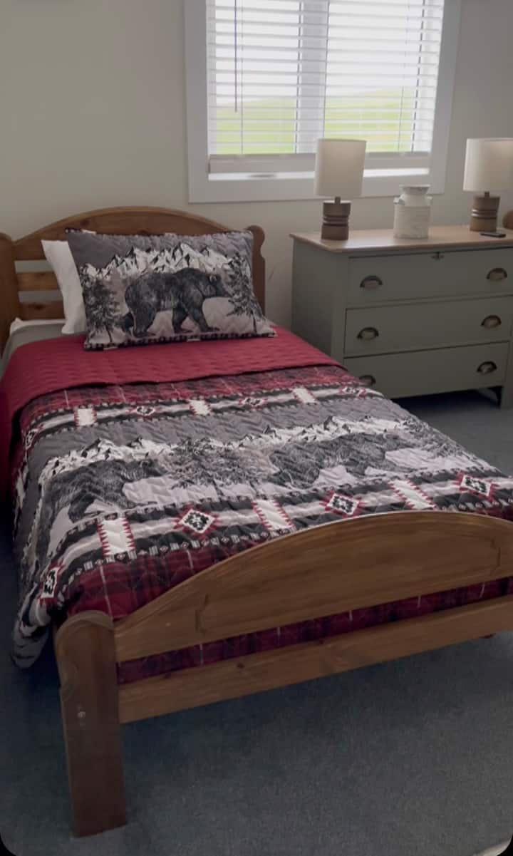 Cozy and inviting, this twin bed is adorned with rustic bear quilt decor. It’s a great spot for children or adults seeking a peaceful night’s sleep, accompanied by a lovely dresser for added convenience