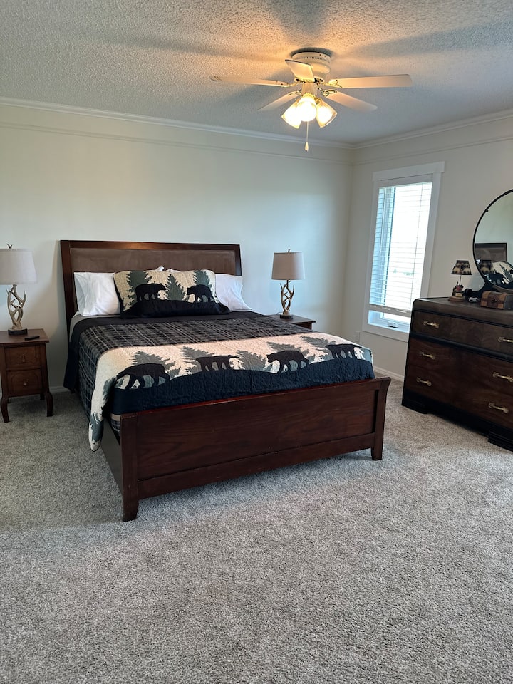 Welcome to the master bedroom, your serene retreat with a cozy queen-size bed and rustic decor. The warm wood and charming dresser make it the perfect space to unwind and recharge!