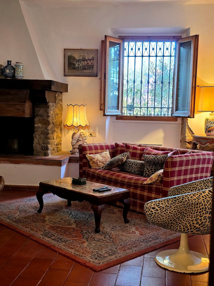 Cozy up in this charming living room! Yet a another space to enjoy your stay. Rustic stone fireplace, plush red plaid sofa, & vintage rug create a warm atmosphere. Unwind and gaze out at the greenery. Perfect quaint retreat to feel at home.