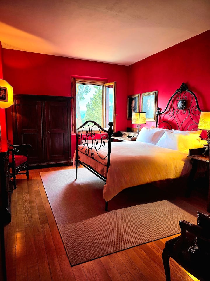 The Red Room affectionately known as The Bogart Room exudes elegance with Italian antiques. This serene retreat boasts a plush queen bed, framed by breathtaking views of the rolling Tuscan hills. High ceilings are accentuated by large-scale artwork.