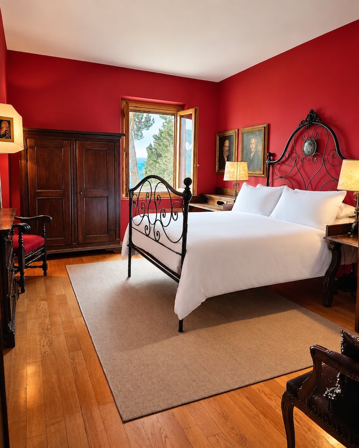 The Red Room affectionately known as The Bogart Room exudes elegance with Italian antiques. This serene retreat boasts a plush queen bed, framed by breathtaking views of the rolling Tuscan hills. High ceilings are accentuated by large-scale artwork.