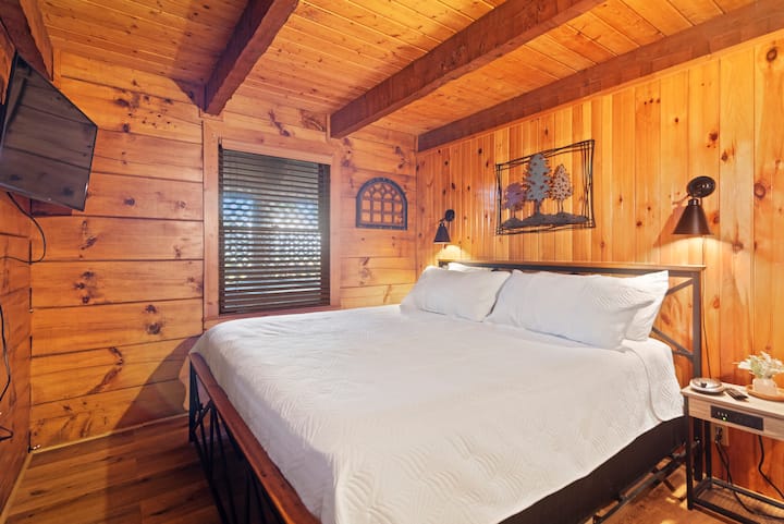 Deslízate en una lujosa cama tamaño king rodeada de un cálido encanto de cabaña, perfecta para parejas o para una noche tranquila después de explorar Pigeon Forge