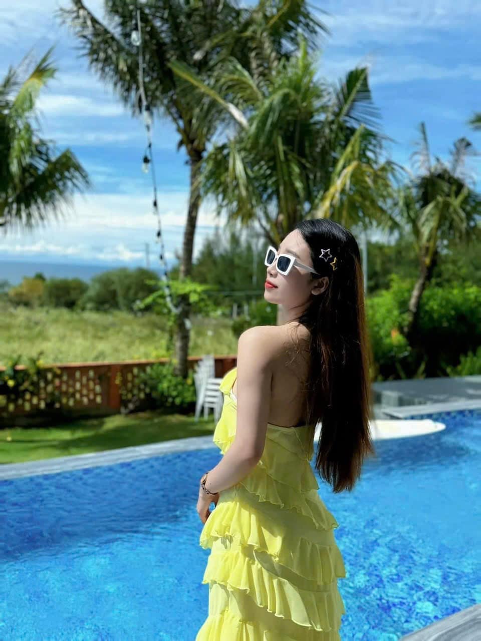 A serene pool area is highlighted, featuring clear blue water surrounded by lush greenery. Tall palm trees frame the scene, and a relaxed atmosphere is suggested by the presence of comfortable seating nearby.