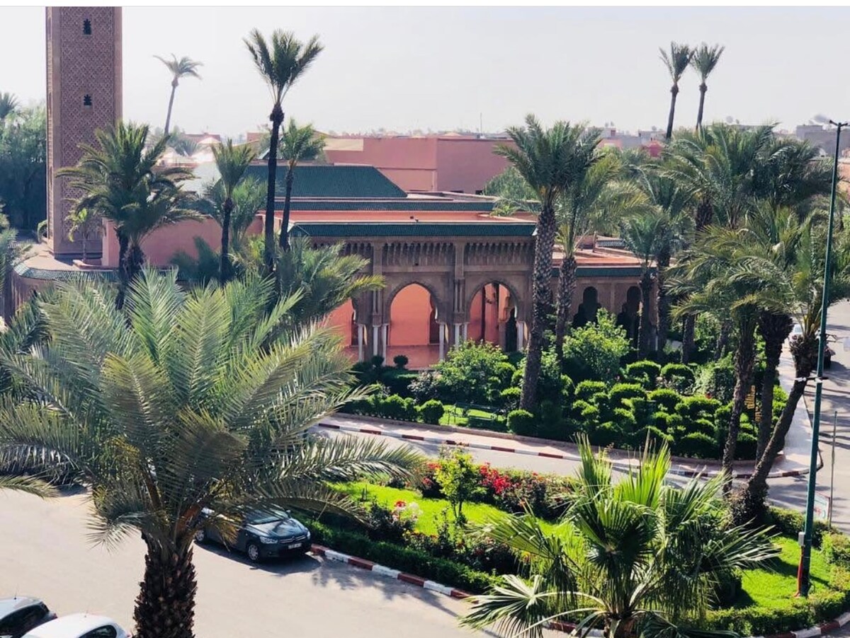 A lush garden area is visible, surrounded by palm trees and decorative shrubs. The design incorporates archways that provide access to covered walkways. A nearby vehicle is parked along the edge of the property, contributing to the tranquil ambiance.