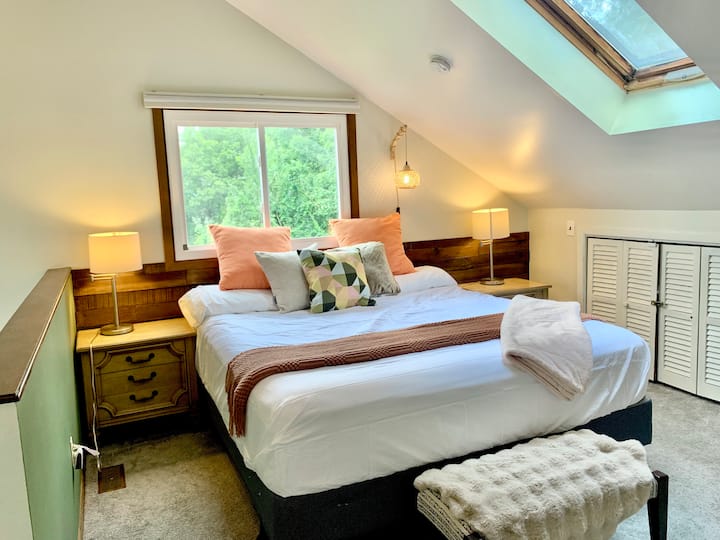 El dormitorio loft temático escandinavo en el loft superior tiene una cama tamaño king, cómodas y sillón y otomana. ¡También viene con su propio baño privado y ducha!