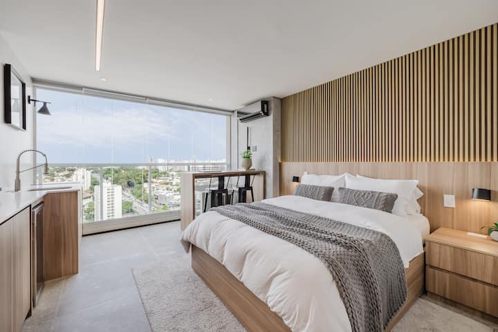 Spacious suite with a king-size bed, a slatted headboard, and city views