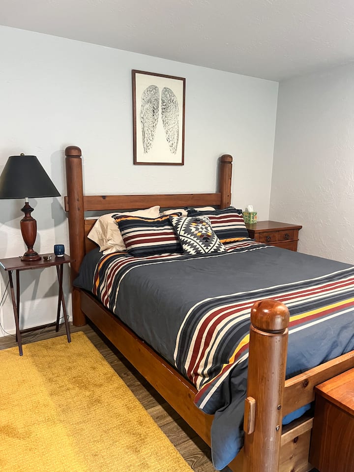 Large primary bedroom with attached bathroom with large walk in shower.  Queen Sized bed with comfortable linen sheets and quilted blanket. Step outside through the sliding door onto the deck and out to the hot tub.