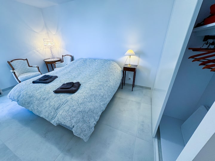 Vue du lit de la Chambre 1 avec lampes de chevet et grande penderie avec cintres