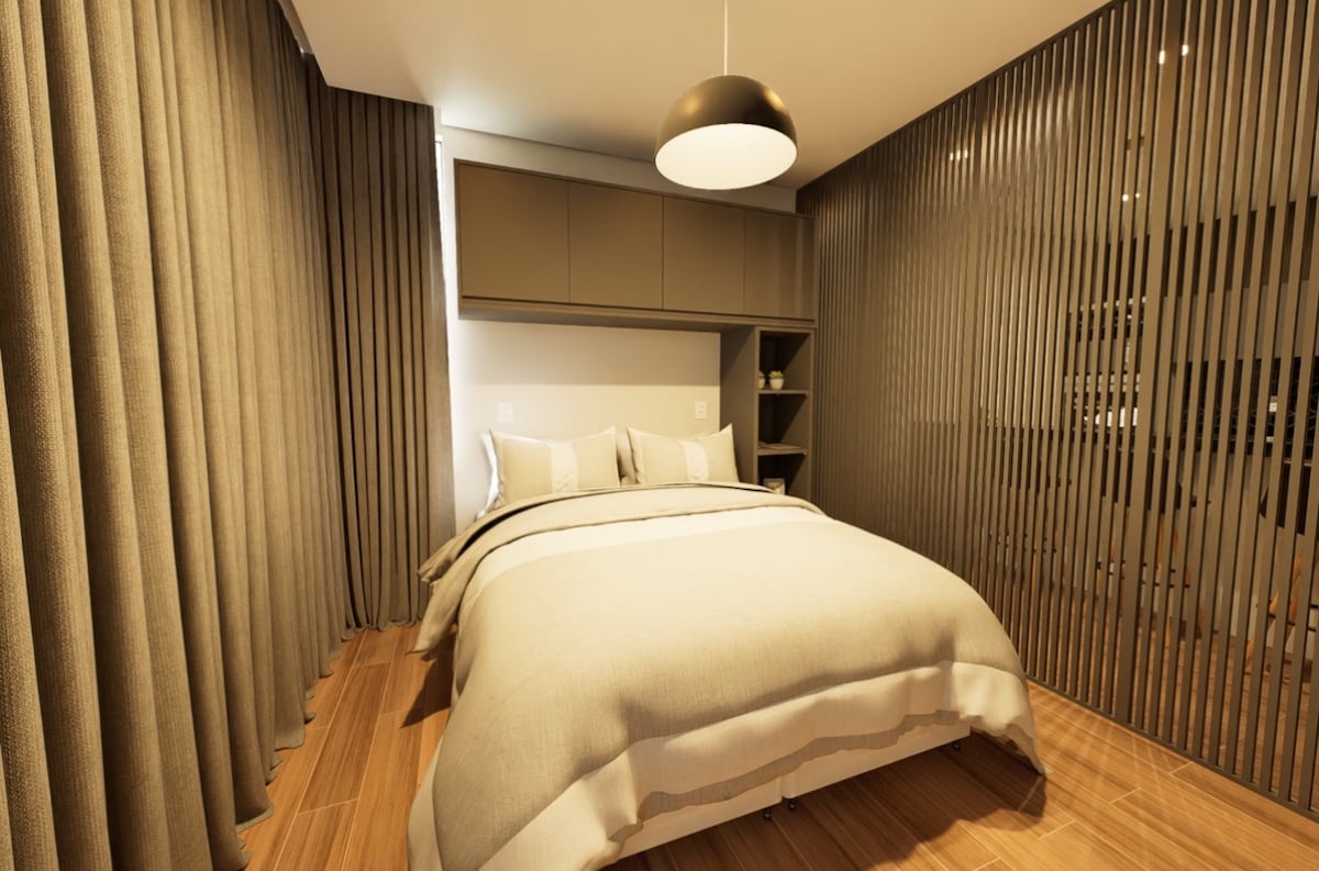 A bed with a neutral-colored comforter is centered in a softly lit room. Light wood flooring contrasts with textured beige curtains. A minimalist shelf is mounted on the wall, and a pendant light provides illumination from above, creating a calm and restful environment.