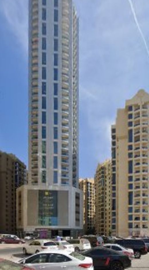 A modern high-rise building is depicted, featuring a sleek glass facade and multiple floors. Surrounding structures showcase a blend of architectural styles. Vehicles are parked in the foreground, and clear blue skies create a bright backdrop.