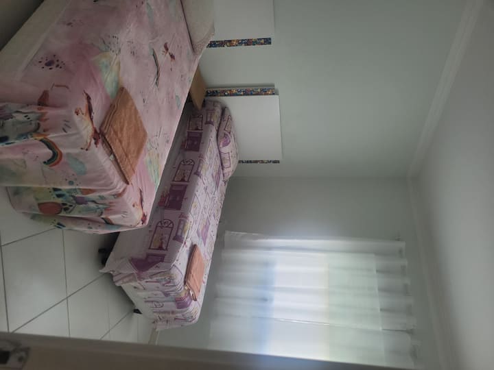Chambre 3 avec deux lits simples, table de chevet, armoire, climatisation, rideaux et stores sur la fenêtre, draps, oreillers, serviettes.