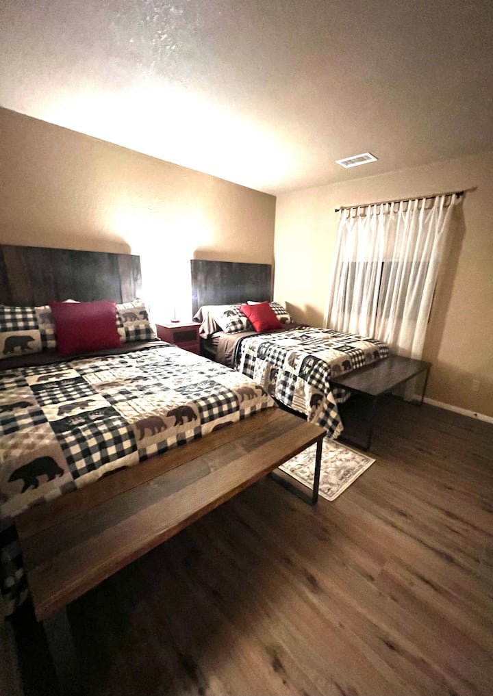 Ხის მყუდრო საძინებელი ოთხამდე სტუმრისთვის, რომელშიც წარმოდგენილია საწოლის ახალი ჩარჩოები, ლეიბები, თეთრეული. Ახალი თავსაფრები და სკამები www.Barn-Walls.com-ისგან.