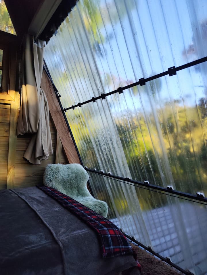 Seu quarto e sua cama em uma cabana A-Frame e porta basculante de frente para a montanha.