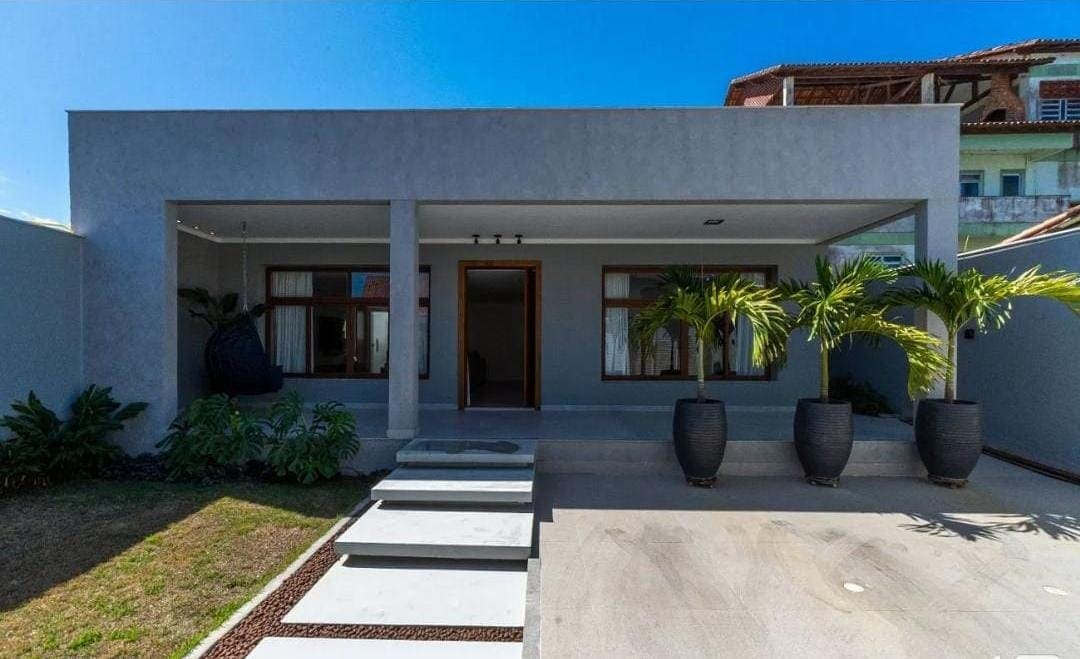 The exterior showcases a modern single-story house with a minimalist design. Large windows allow natural light to fill the interior. Smooth stone steps lead to a covered entryway, flanked by decorative plant pots. A manicured lawn surrounds the property, providing a welcoming entrance.