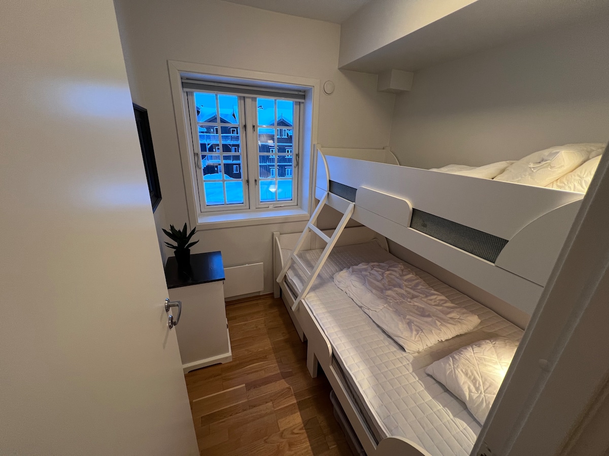 Krevat 120 cm i gjerë në fund dhe krevat 80 cm i gjerë në krye me një perde të errët. Fotografia është bërë me zmadhim 0,5 herë në një iPhone për të kapur një kënd më të gjerë dhe për të ofruar një përmbledhje më të mirë të dhomës.