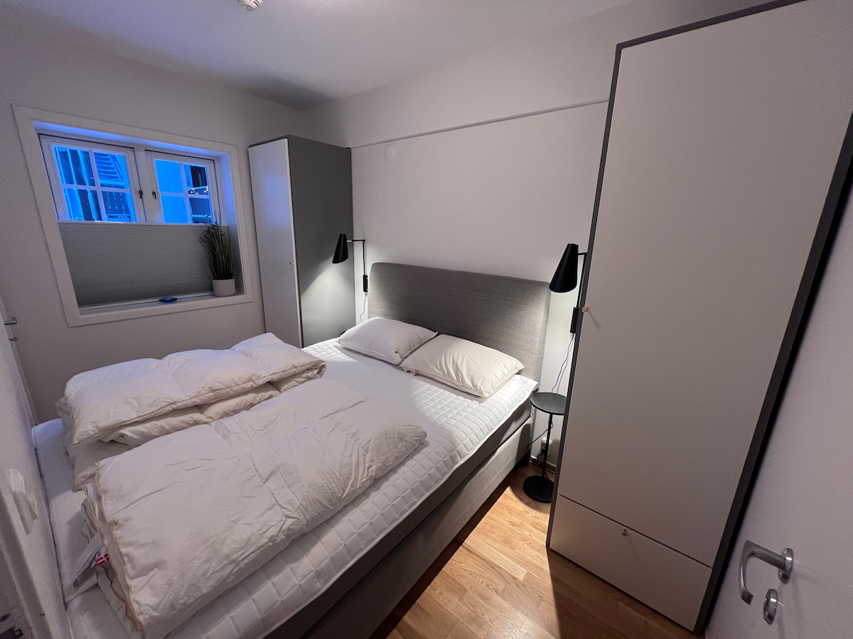 Krevat 150 cm i gjerë me perde të errëta. Fotografia është bërë me zmadhim 0,5 herë në një iPhone për të kapur një kënd më të gjerë dhe për të ofruar një përmbledhje më të mirë të dhomës.