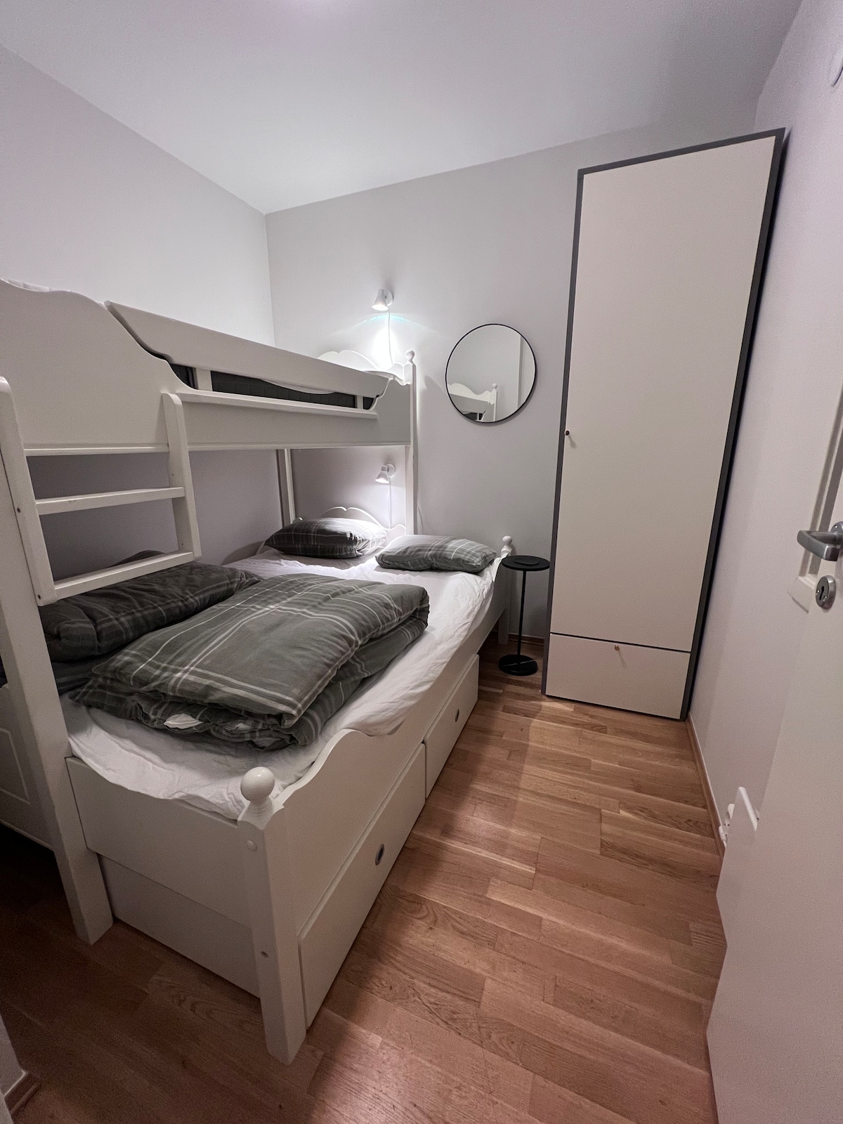 Krevat 150 cm i gjerë në fund dhe krevat 90 cm i gjerë një majë me perde të errëta. Fotografia është bërë me zmadhim 0,5 herë në një iPhone për të kapur një kënd më të gjerë dhe për të ofruar një përmbledhje më të mirë të dhomës.