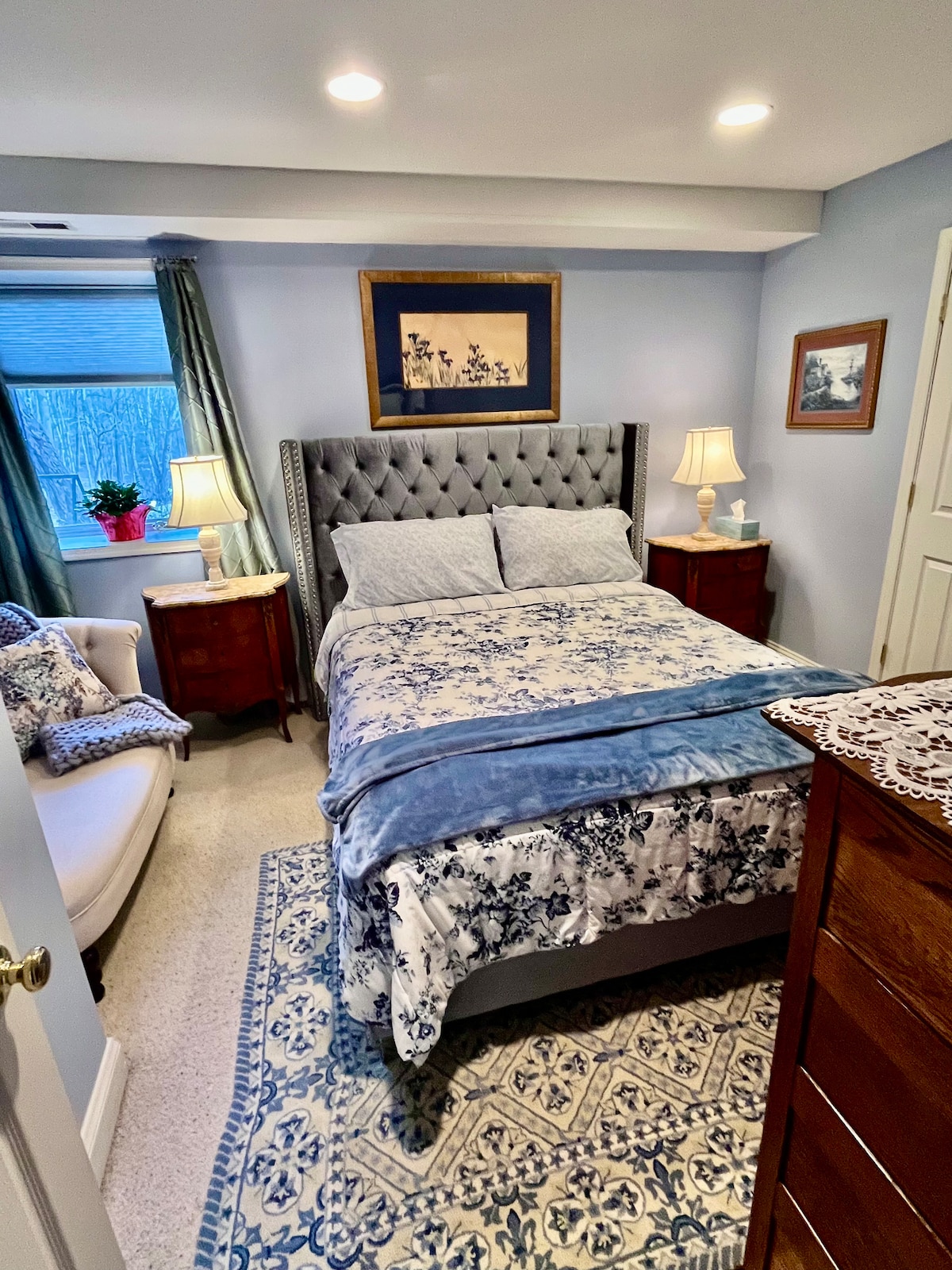 Krevat dopio me dyshek të rehatshëm të ri DreamCloud dhe shtroja luksoze Devereux.  Komodina antike franceze me intarsia, me sipërfaqe mermeri dhe llamba alabastri.  Akvarel me zambakë japonezë mbi krevat. 