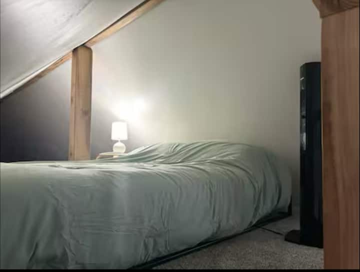 ¡Póngase cómodo en el loft! Estación de carga ubicada junto a la cama y ventilador portátil. Este es un loft abierto al que se accede por la escalera; no es un dormitorio completamente privado con puerta.