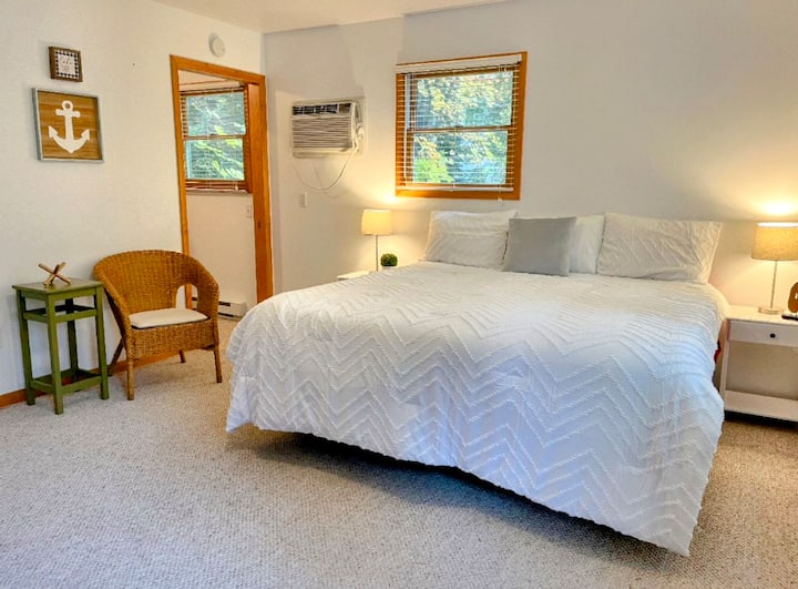 This large area (guest cottage) has a king sizebed, TV, and air conditioning unit. To the left there is a full bathroom,  and then a bedroom with a twin over full-size bunk bed.