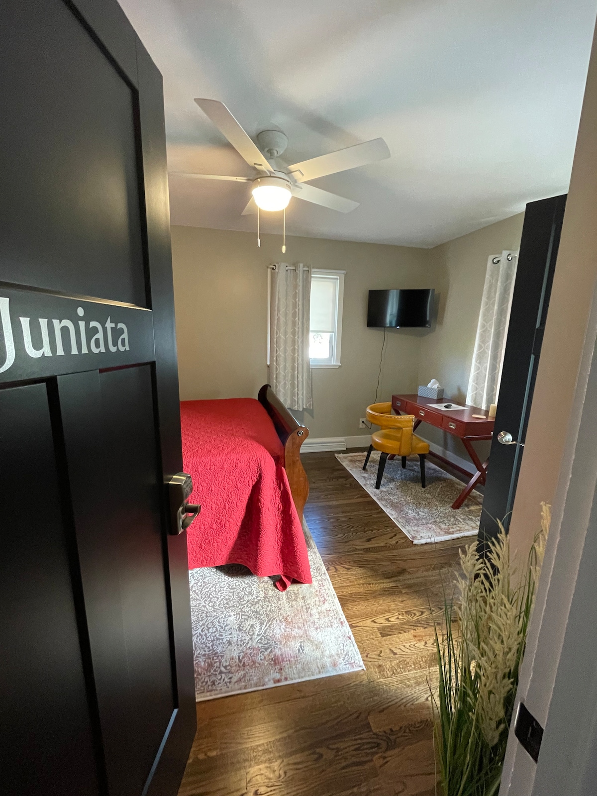 Chambre Juniata avec salle de bains privative. La porte est équipée d'une serrure d'entrée sans clé. Bureau associé à une chaise de restaurant vintage confortable. Télévision Roku sur support mural pivotant.