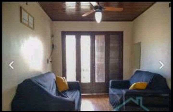 A bright living area features two comfortable sofas with yellow cushions. Light-colored walls are complemented by a wooden ceiling. Double doors lead to an outdoor space, enhancing natural light and inviting fresh air into the room.