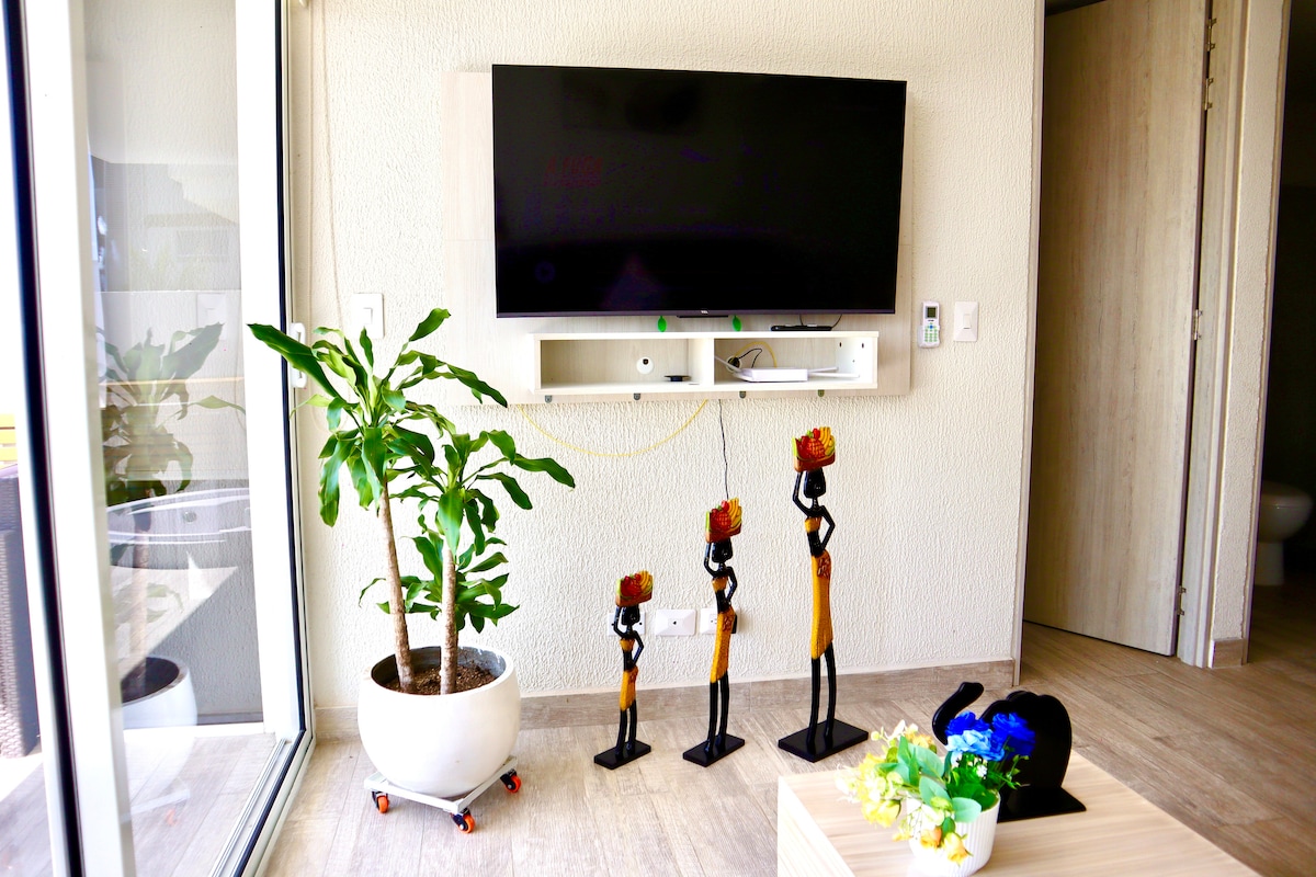 Góc ấm cúng với TV gắn tường, đồ trang trí nhiệt đới và một chút cây xanh — hoàn hảo để thư giãn sau khi khám phá sự kỳ diệu của Cartagena