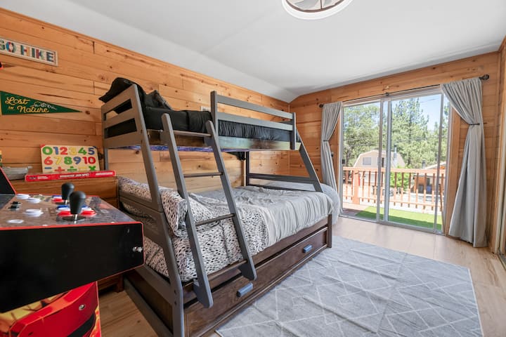 Kitanda chetu cha ghorofa tatu kina sehemu ya juu ya ghorofa, imejaa katikati na pacha wa ghorofa hapa chini (ambayo inafaa zaidi kwa mtoto). Kwenye roshani, utapata viti vya kufurahia Mionekano ya Mlima na taa za kamba zinazoendeshwa na kitufe cha kushinikiza