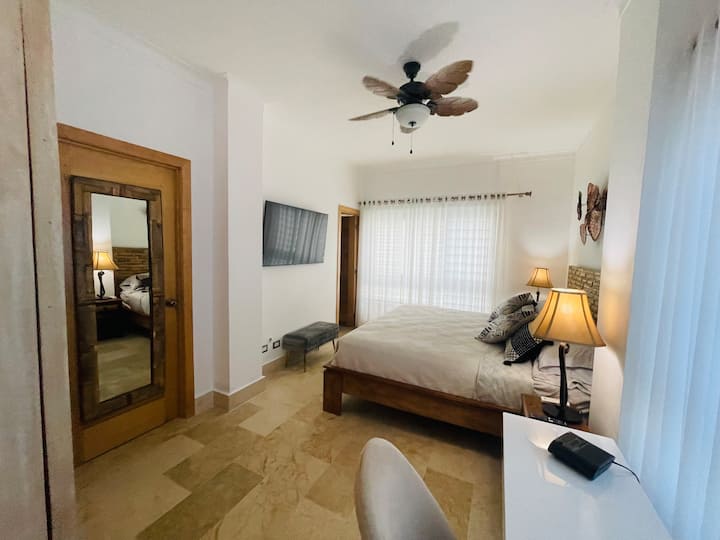 חדר שינה ראשי, עם מיטת קינג סייז, טלוויזיה וחדר רחצה.