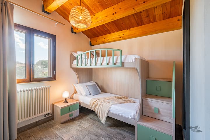 غرفة نوم ساحرة تتميز بسرير بطابقين مريح وإطلالة مبهجة على الريف الصقلي. يخلق السقف الخشبي الدافئ والتصميم المدروس جوًا جذابًا ومريحًا، وهو مثالي للاسترخاء والاستمتاع بالمناظر الطبيعية الريفية الهادئة.