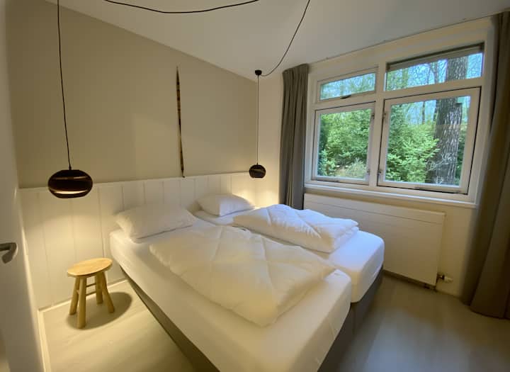 חדר שינה מרווח עם נוף לגינת היער. מיטת קפיצים Swiss Sense עם מזרני מט ומצעים טעימים