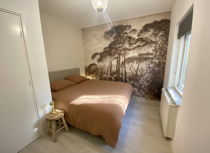 מיטה זוגית בסגנון שווייצרי עם מזרן קשיח ונוף יפהפה דרך שני החלונות לגינת היער