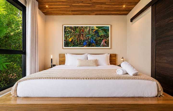 Isang tahimik na king bedroom na may mga premium na linen na may kalidad ng hotel, mga handcrafted na detalye na gawa sa kahoy, orihinal na likhang-sining na tropikal, at magagandang tanawin ng gubat—idinisenyo para sa nakakapagpahingang tulog sa isang tahimik na lugar sa Costa Rica