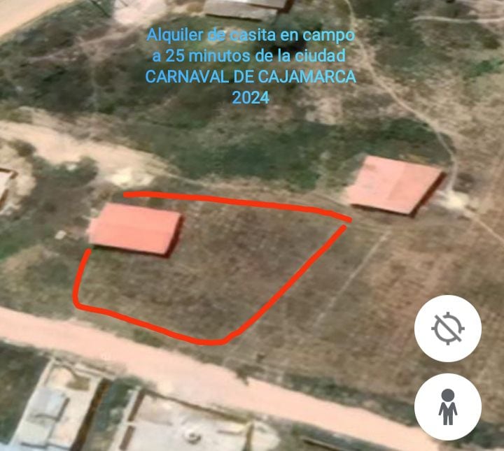 An aerial view displays two buildings situated on a grassy area, surrounded by dirt pathways. The layout showcases a spacious outdoor setting, ideal for gatherings and relaxation, with ample open space surrounding the structures.