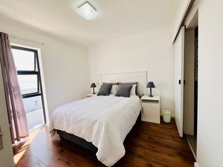 Quarto principal com cama queen size confortável, roupa de cama fresca e um design calmo e neutro para noites tranquilas.