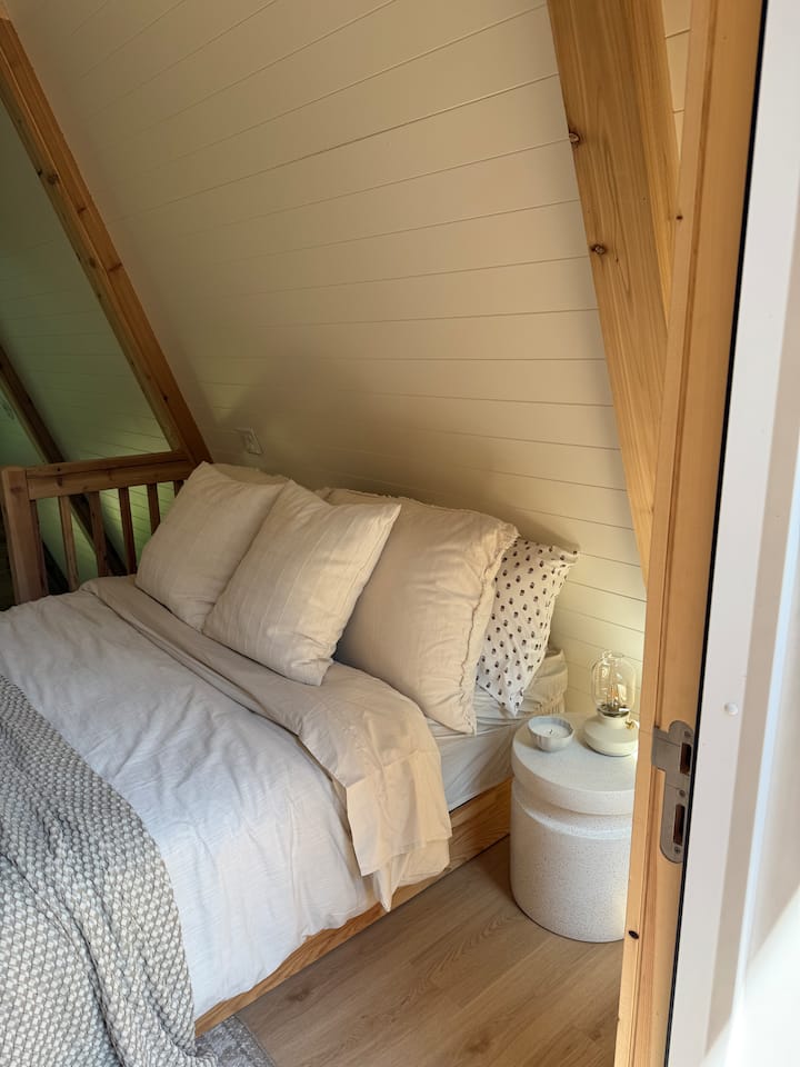 Cozy queen bed up in our lofted bedroom. Access to our outdoor balcony that overlooks the woods!