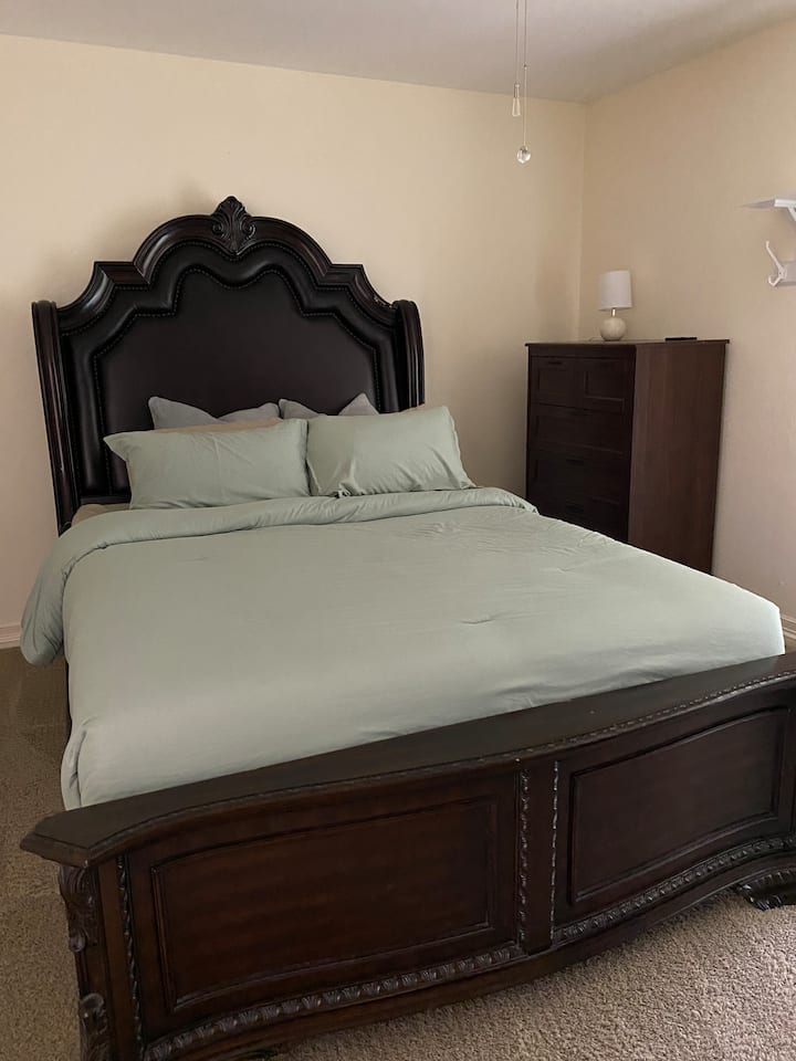 La camera da letto matrimoniale è spaziosa e presenta un elegante letto matrimoniale, arricchito da biancheria da letto morbida e invitante e cuscini decorativi. Accanto, trovi un comò con cassetti per riporre gli oggetti. 
