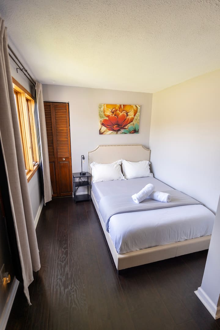 מיטה זוגית, קומה 1, עם וילונות האפלה וכיסא נוי. 